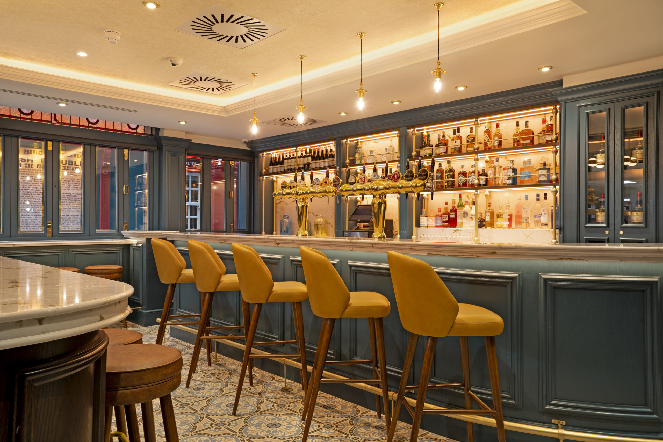 Stylish hotel bar with gold taps and high stools at The Mercantile Dublin, a top bar near The Olympia Theatre.