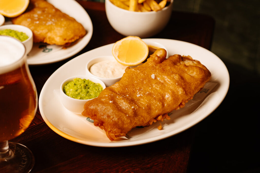 BEER BATTERED HADDOCK served with Fries, peas, tartare sauce, curry sauce from The Mercantile Hotel, the best food in the city . If you're looking for where to eat in Dublin, save your spot here 